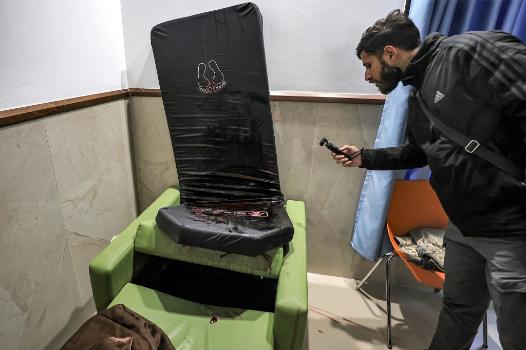 A man films blood stains on a mattress and chair at the Ibn Sina hospital in Jenin