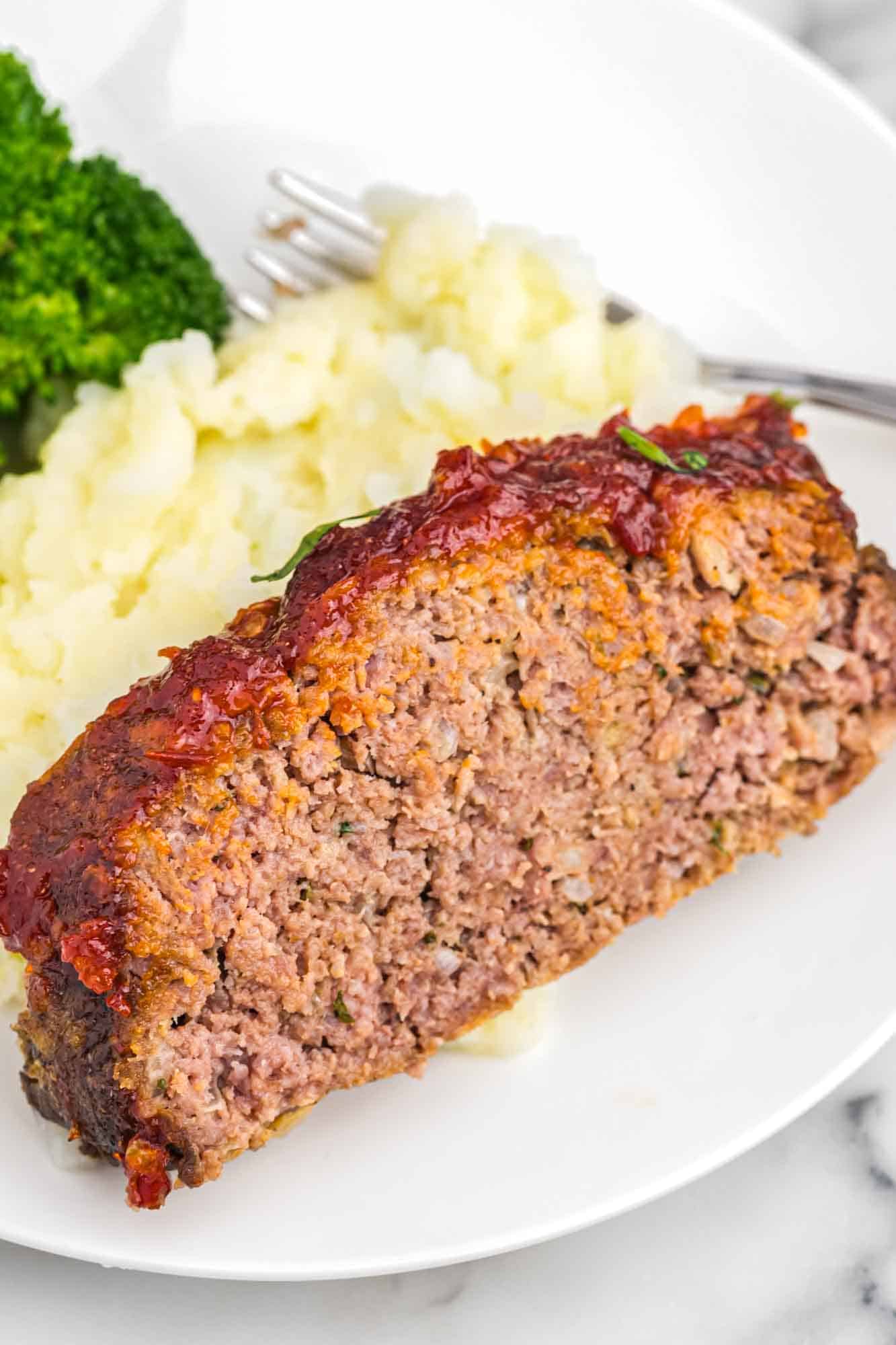 A slice of meatload served with mashed potatoes and steamed broccoli