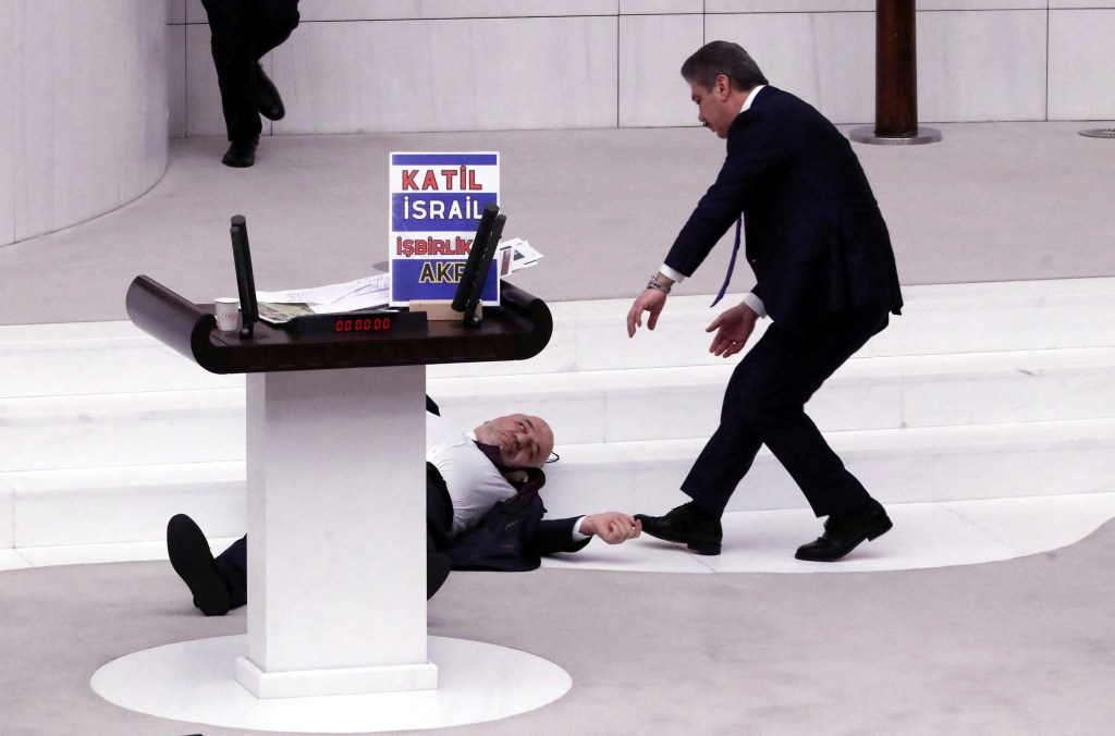 Turkey's opposition Felicity Party (Saadet) lawmaker Hasan Bitmez lies on the floor next to a stand with a placard after collapsing following his speech criticizing the government's policy towards Israel, at the Turkish parliament in Ankara