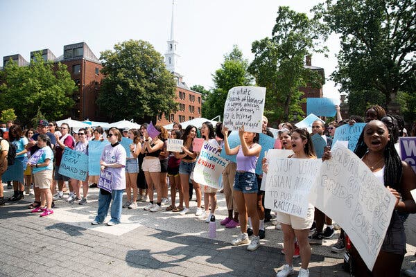 A crowd of mostly young adults holding signs in support of affirmative action at an outdoor rally.