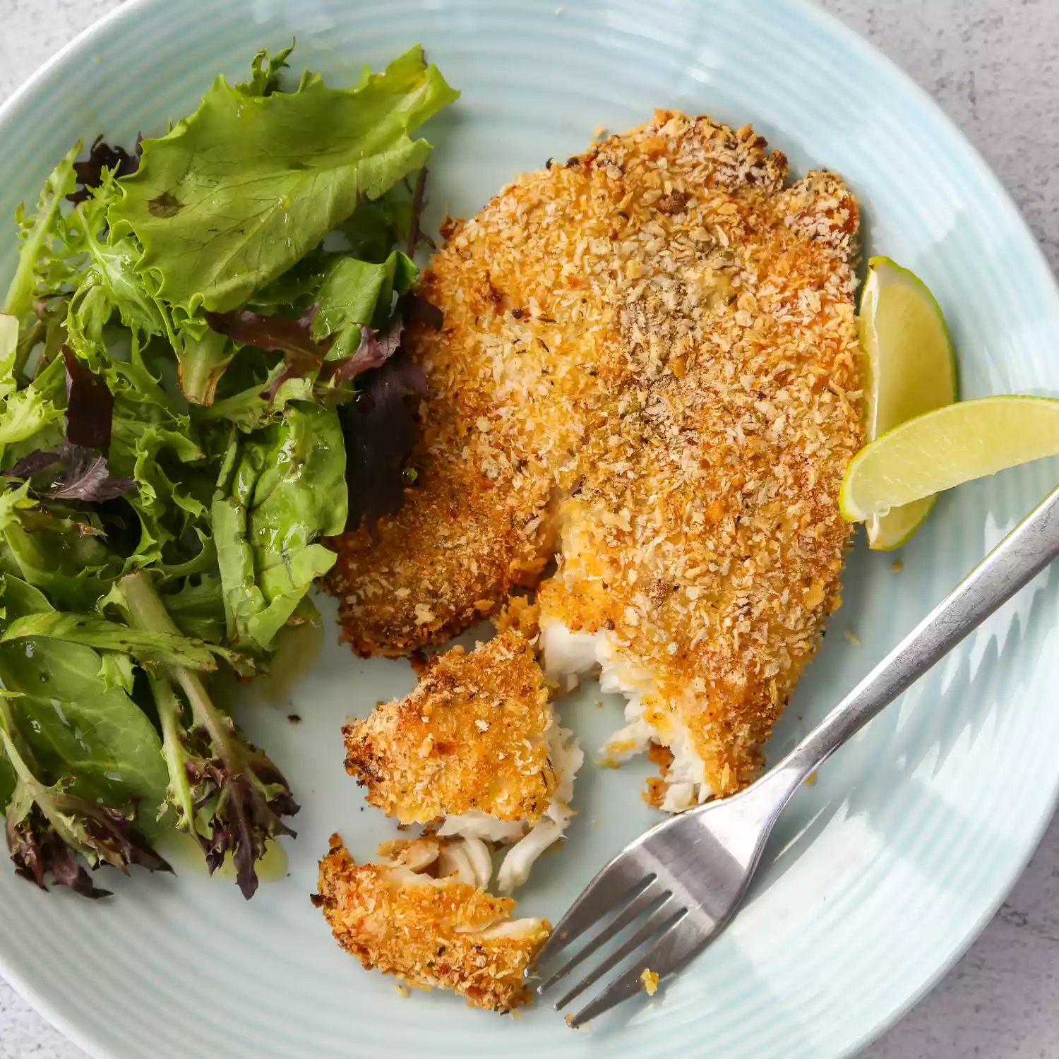 Crunchy panko-crusted baked tilapia with salad greens on a plate
