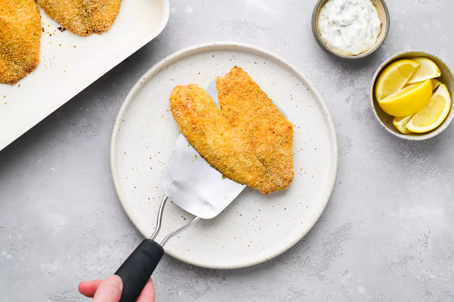 Crunchy panko-crusted baked tilapia on a spatula on a plate