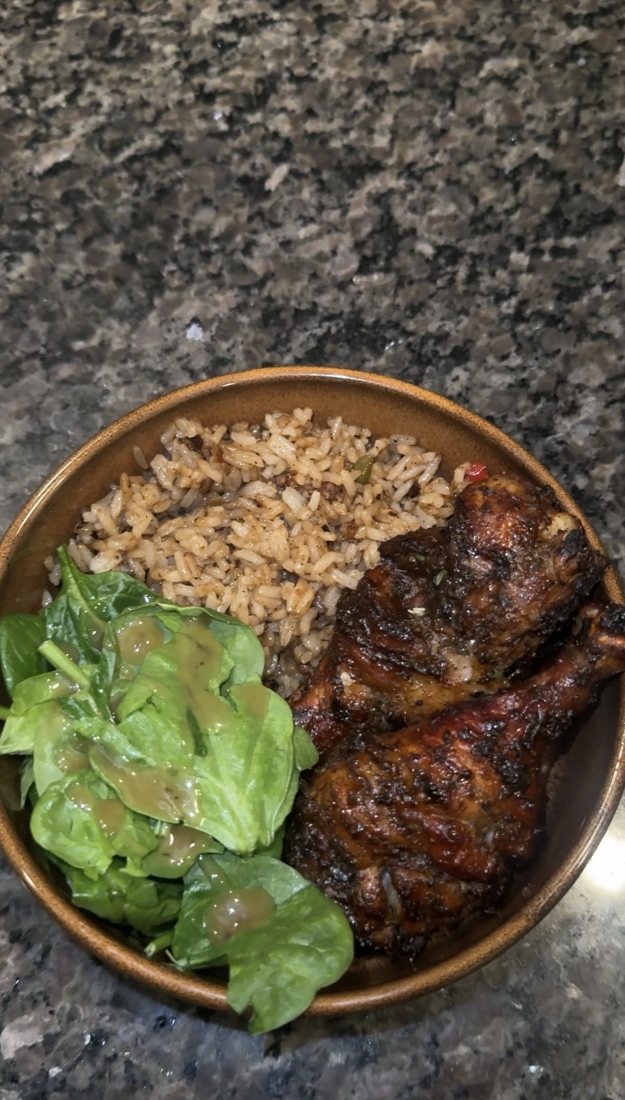 Oven-grilled chicken drumsticks plated with rice and salad in a bowl