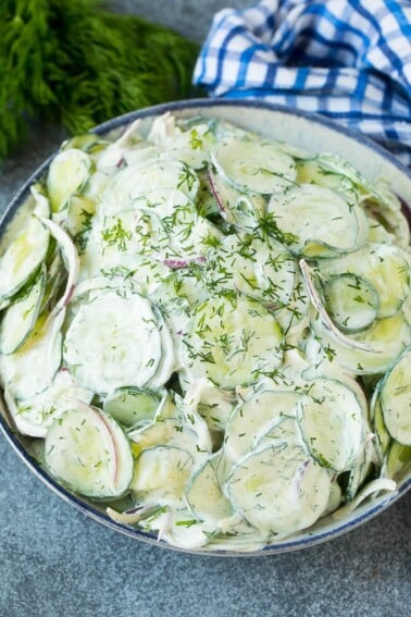 Creamy cucumber salad with red onion and dill, topped with fresh herbs for garnish. Creamy cucumber salad with red onion and dill, topped with fresh herbs for garnish.