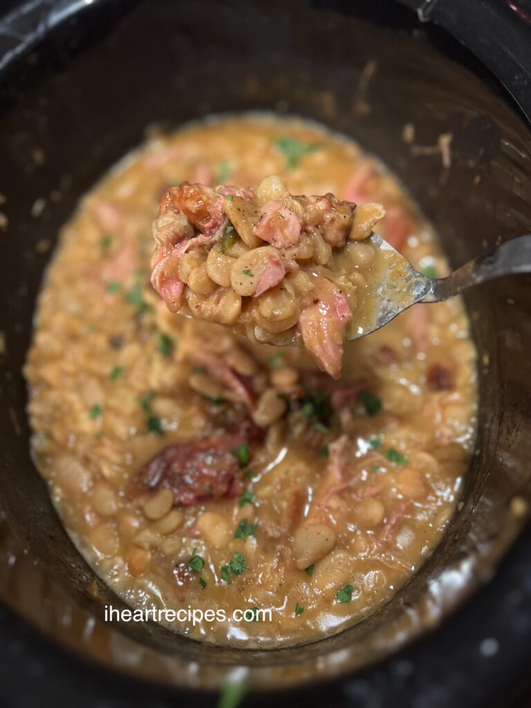 A serving of butter beans and tender turkey in a golden broth hovers over a large pot.