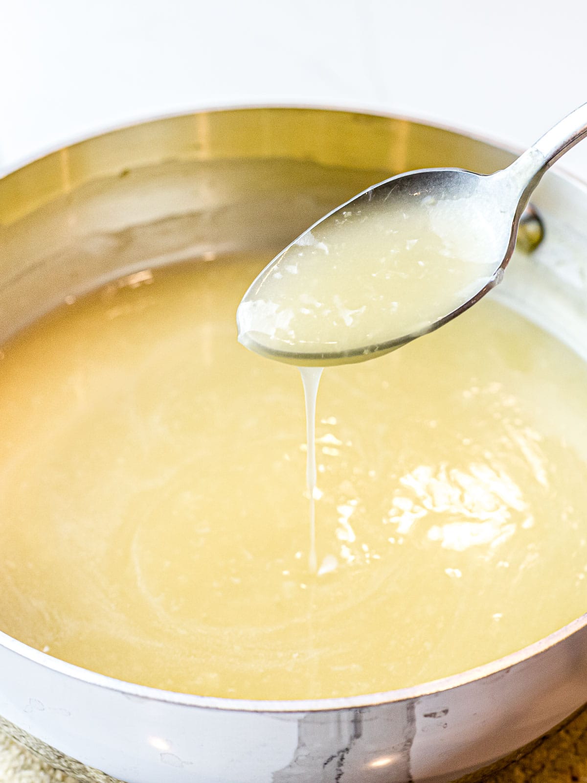 Chinese white sauce poured off a spoon into a pot