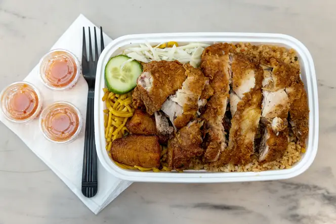 A container with chicken chow mein is on a table at Brown Betty Restaurant