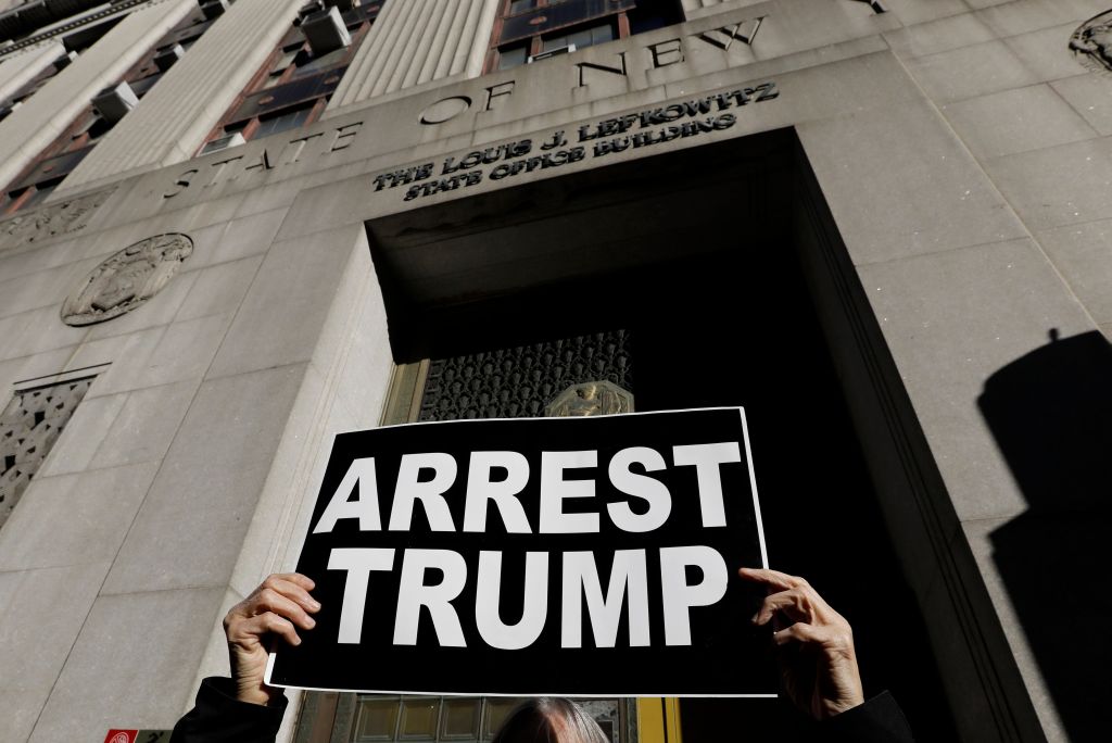 A protester holds up a sign outside the New York State Louis Lefkowitz office building where grant jury testimony is being heard in the possible indictment of former President Donald Trump on March 20 in New York City. 