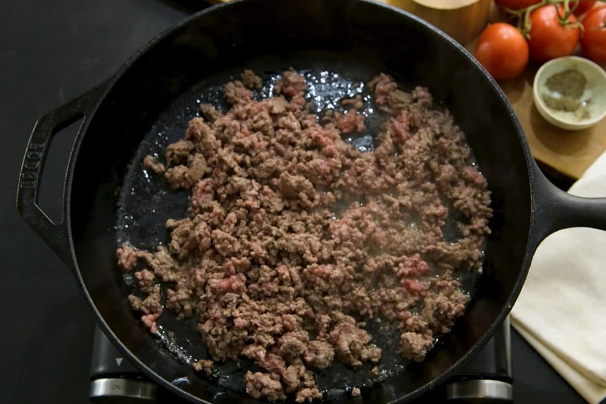 Browned ground beef in cast iron pan.