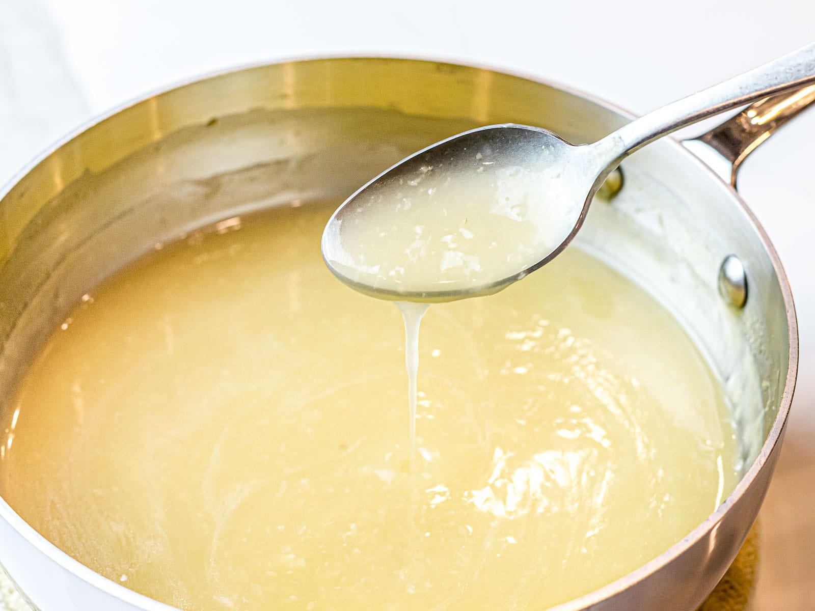 clear Chinese stir fry sauce poured off a spoon into a pot