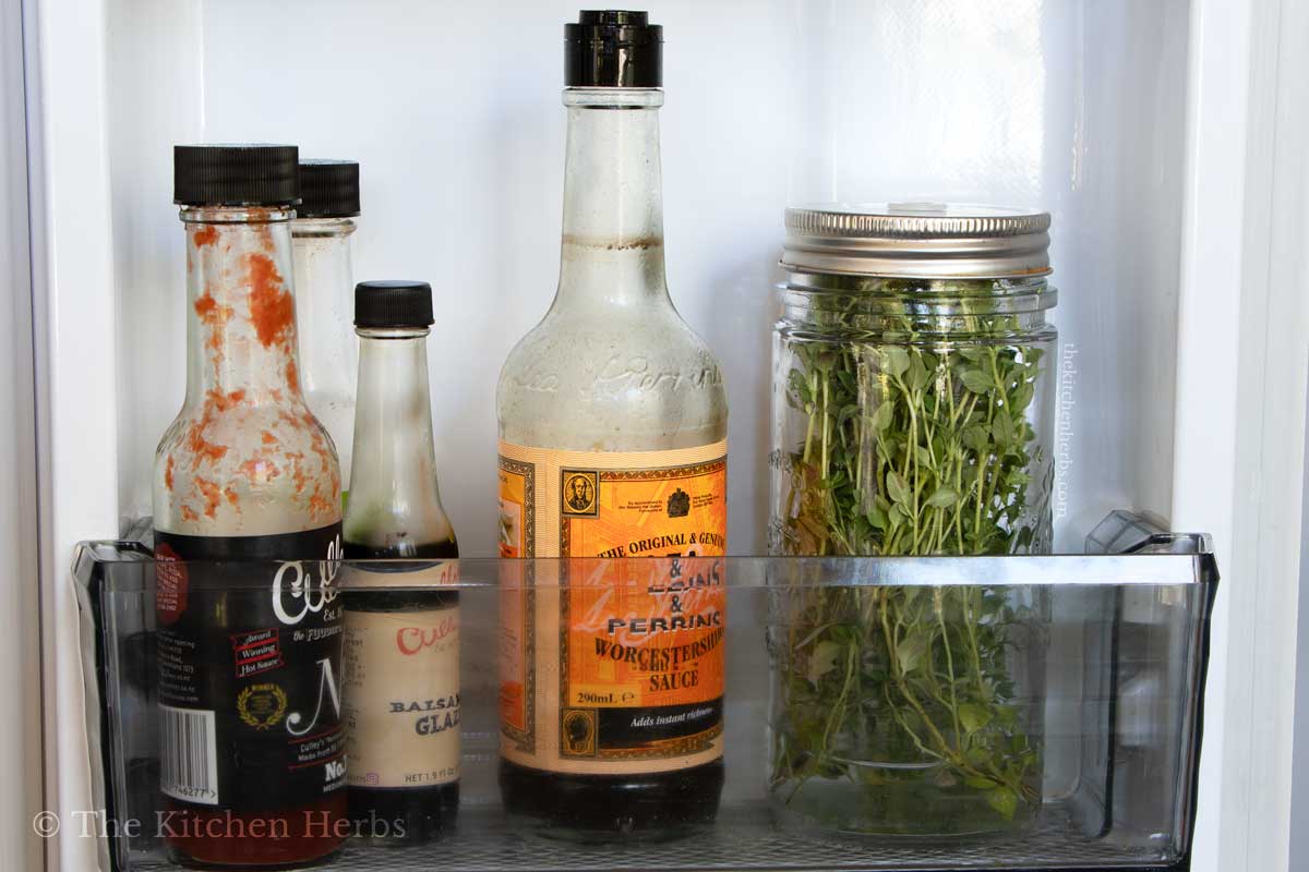 A jar with fresh thyme in a fridge door. 