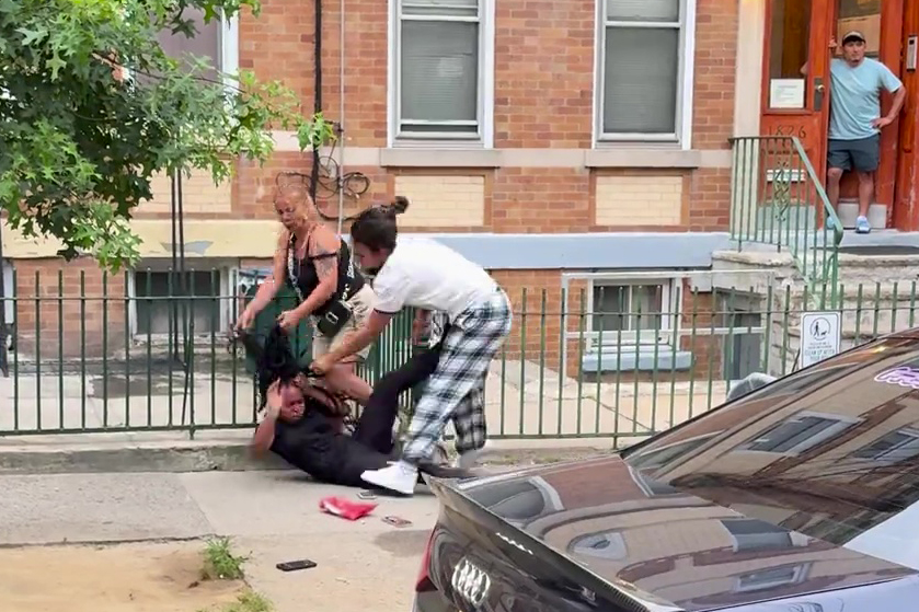 A woman being assaulted by two other women on a sidewalk.