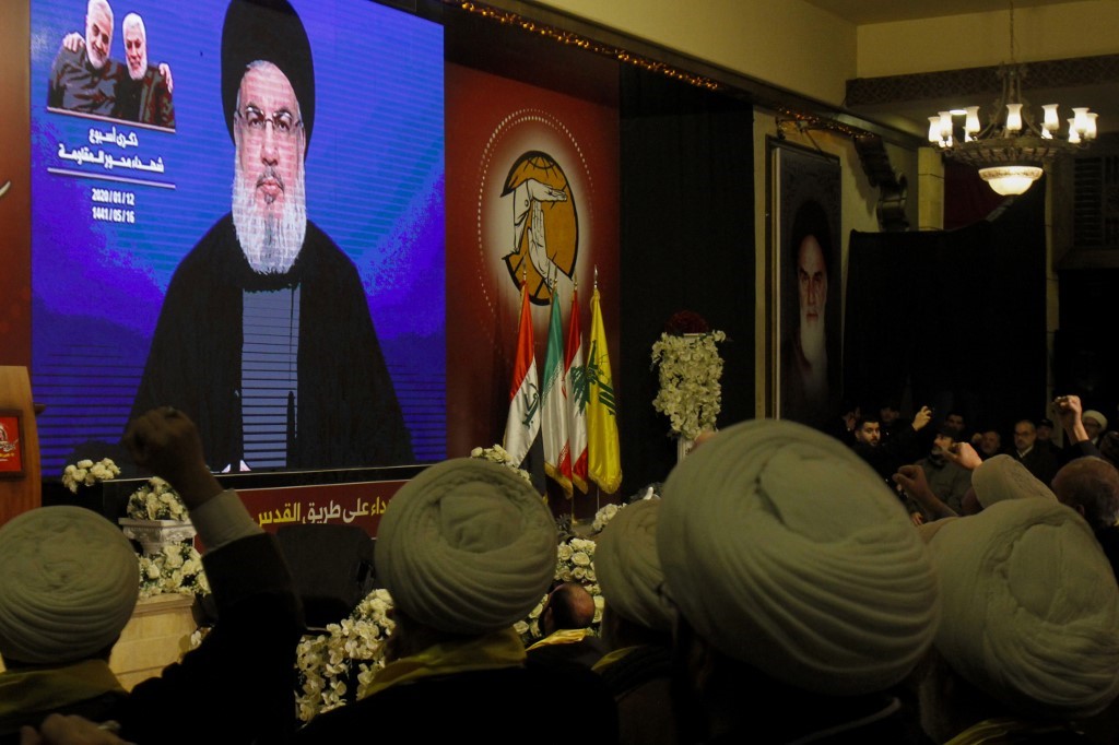 Supporters of the Hezbollah movement watch as the movement's leader Hasan Nasrallah delivers a speech on a screen in the southern Lebanese city of Nabatieh on 12 January (AFP)