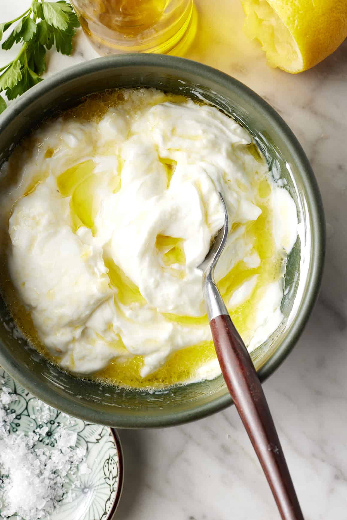 Yogurt, lemon juice, and olive oil in a bowl with a spoon