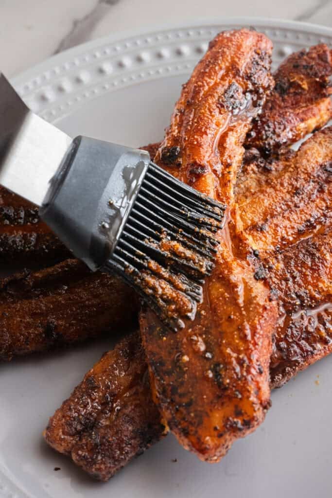 Nashville Hot seasoning being brushed on pork belly.