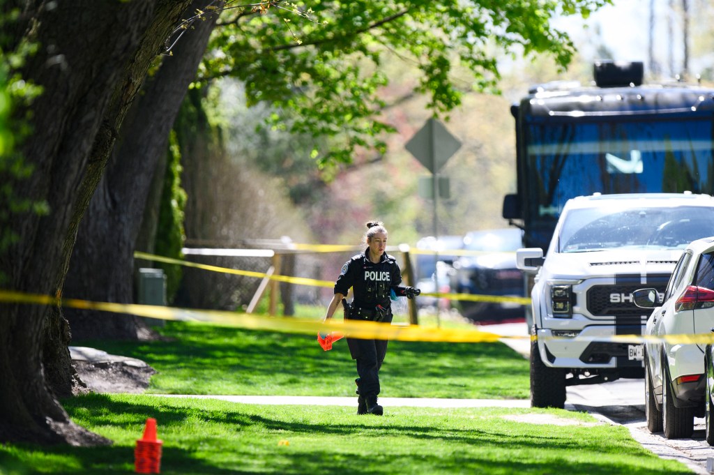 A police officer walks across a front lawn, taped off following the shooting.