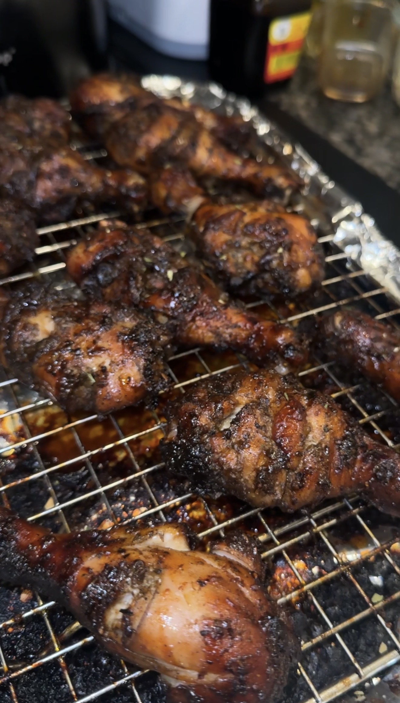 Oven-grilled chicken drumsticks on a wire rack, dark caramelized edges from the broiler