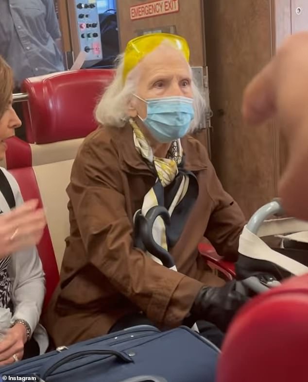 The unidentified woman, dressed in a brown coat, multicolored scarf, blue facemask and bright yellow glasses on her head, watched on as O'Keefe was dragged off the train