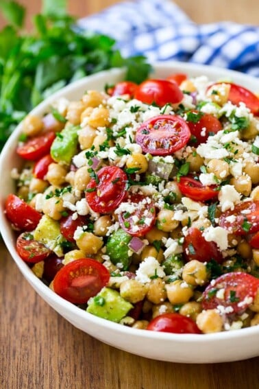 A bowl of chickpea salad with tomatoes, cucumber, avocado, feta cheese and herbs. A bowl of chickpea salad with tomatoes, cucumber, avocado, feta cheese and herbs.