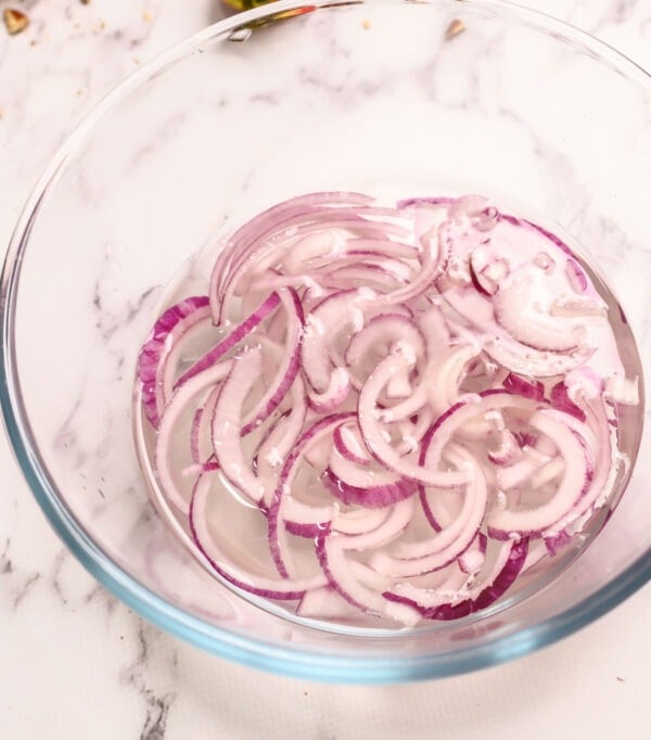 Sliced red onions in a glass mixing bowl
