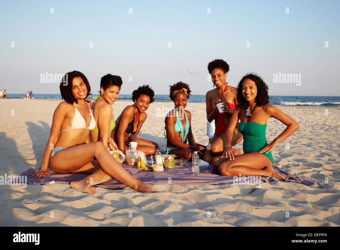 women-relaxing-together-on-beach-DEP9F4.jpg