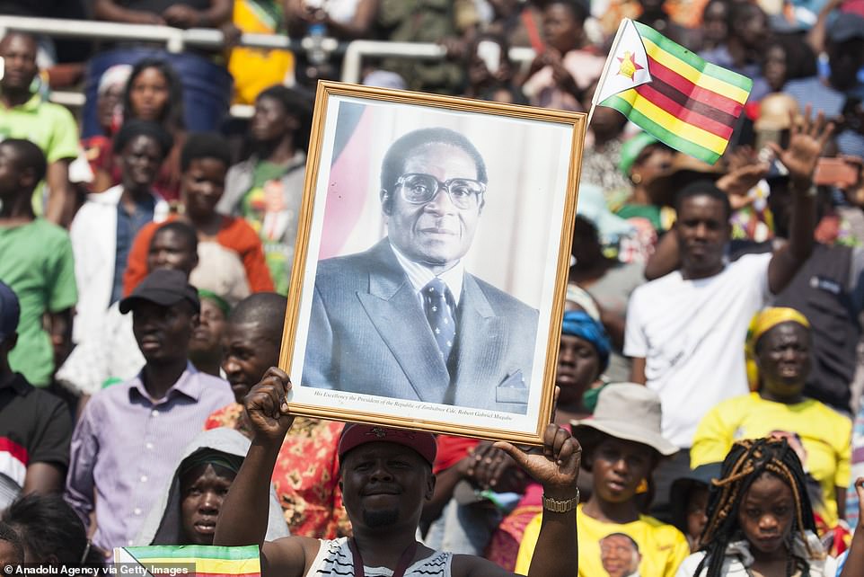 19042308-7514931-A_citizen_holds_a_photo_of_Zimbabwe_s_late_former_president_Robe-a-43_1569675691039.jpg