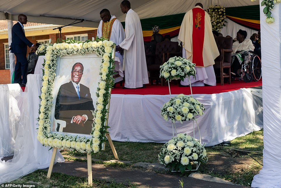 19043096-7514931-Priests_stand_near_a_portrait_of_Mugabe_as_they_prepare_for_the_-a-41_1569675691036.jpg