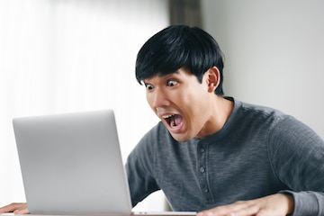 shocked-surprised-asian-man-looking-laptop-computer-screen-sitting-living-room_59017-675.jpg