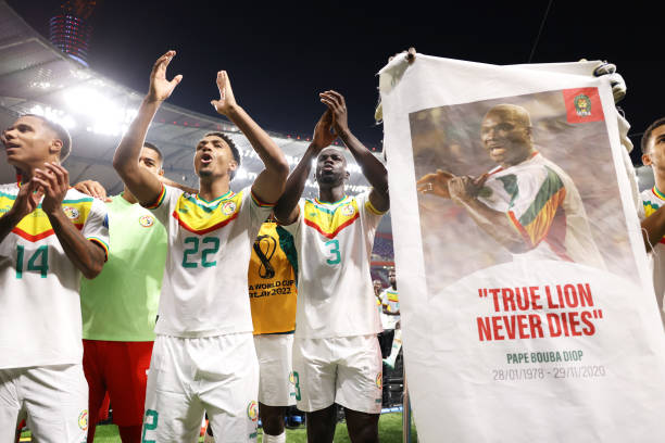 senegal-players-applaud-fans-with-a-banner-of-papa-bouba-diop-on-the-2nd-anniversary-of-his.jpg
