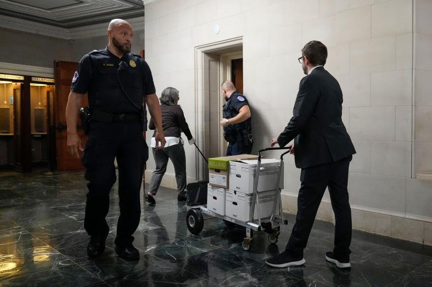 A picture of staff members move boxes of documents from the hearing room to the office of the House Ways and Means Committee.