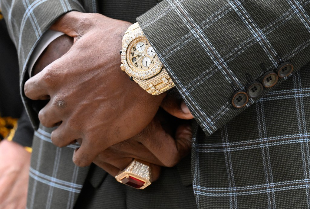 Close up of a man's hands wearing a gold watch.