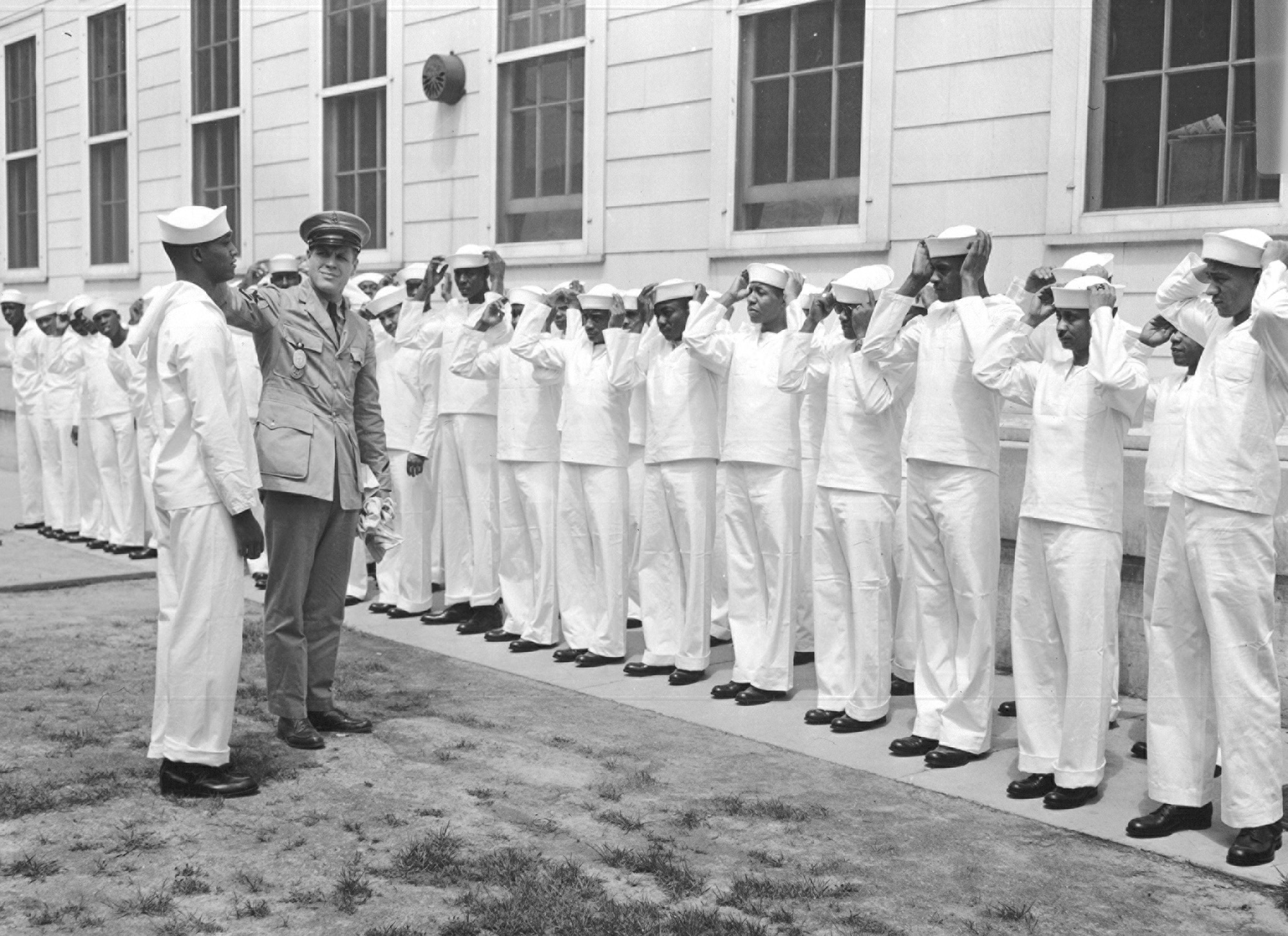 New recruits receive their first lecture on Naval procedure. Chief Specialist R. W. Wsllid, in khaki, demonstrates the proper way to wear a Navy hat. 9-9-42