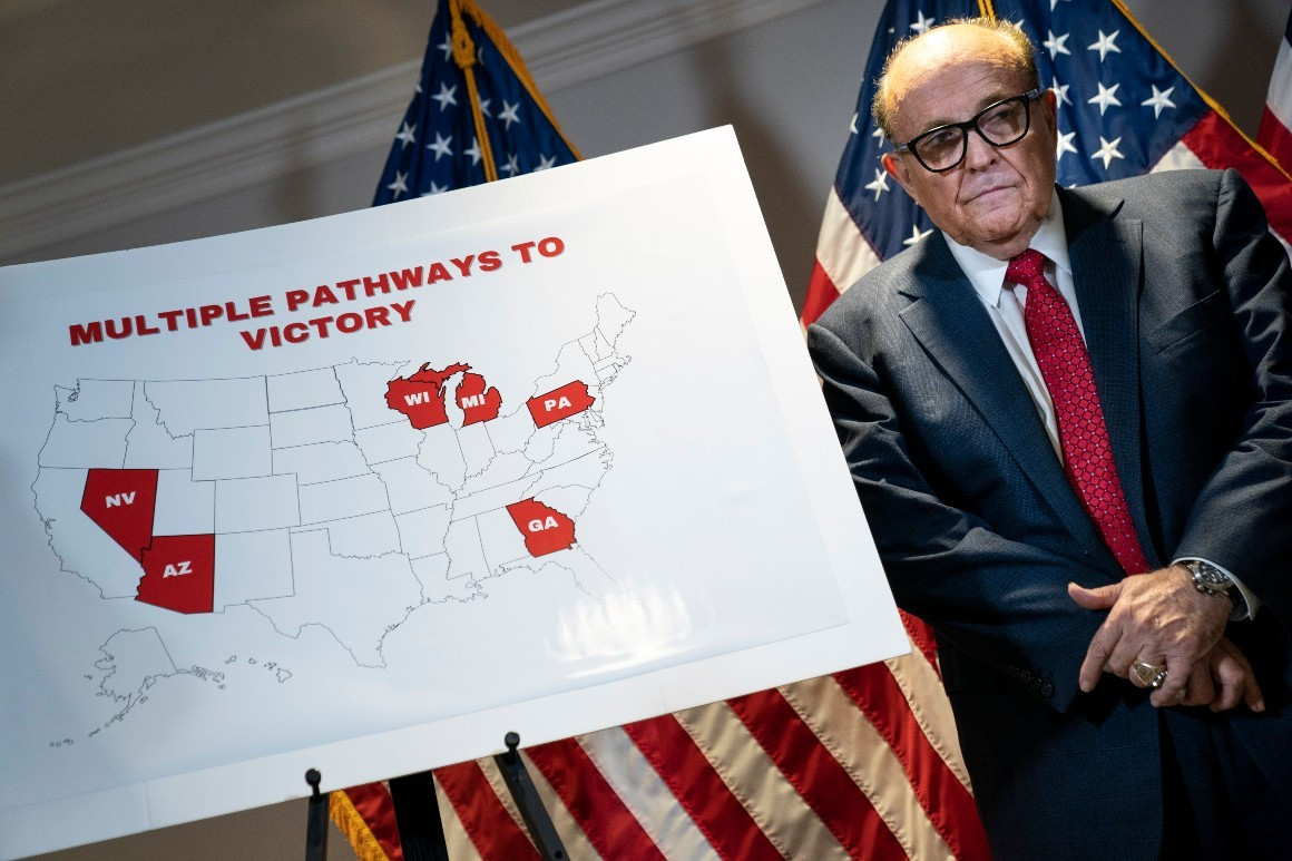 Rudy Giuliani stands next to a map during a press conference.