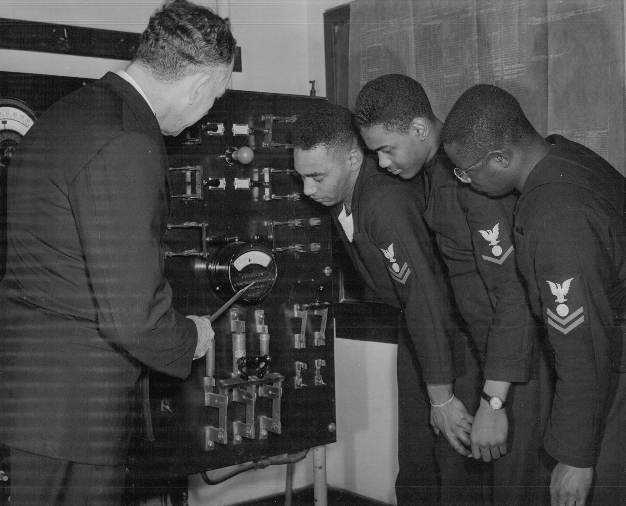 From right: Nathaniel O. Dyson, Richard Hubbard, and John W. Reagan, three electrician’s mates, listen as Chief Electrician’s Mate John E. Taylor explains the workings of the power system that they would be working with when serving aboard the USS Mason. Reagan would be diverted to officer candidate school shortly after this photo was taken.