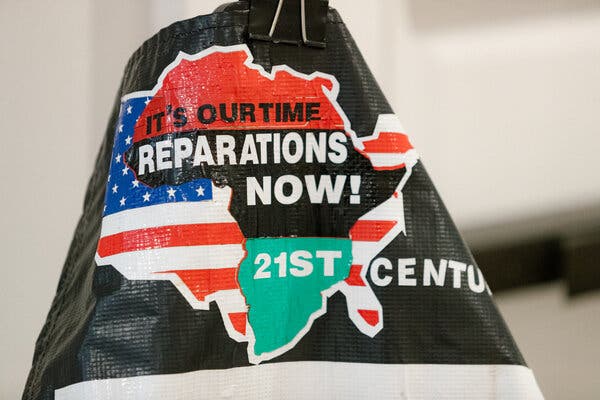A sign displaying Africa and the United States that reads, “It’s our time reparations now! 21st century.”