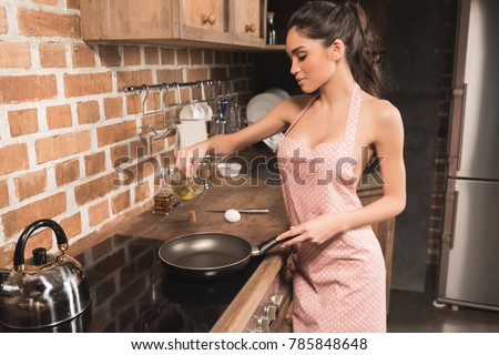 stock-photo-sexy-young-woman-in-apron-pouring-oil-on-frying-pan-in-kitchen-785848648.jpg